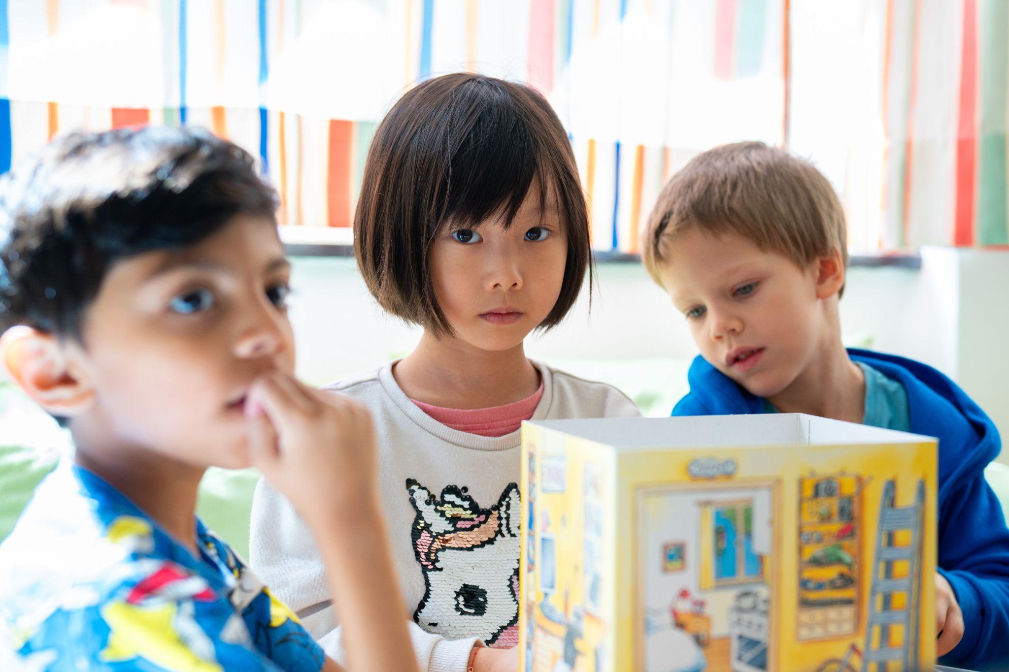 Drei Kinder betrachten gemeinsam ein Bilderbuch